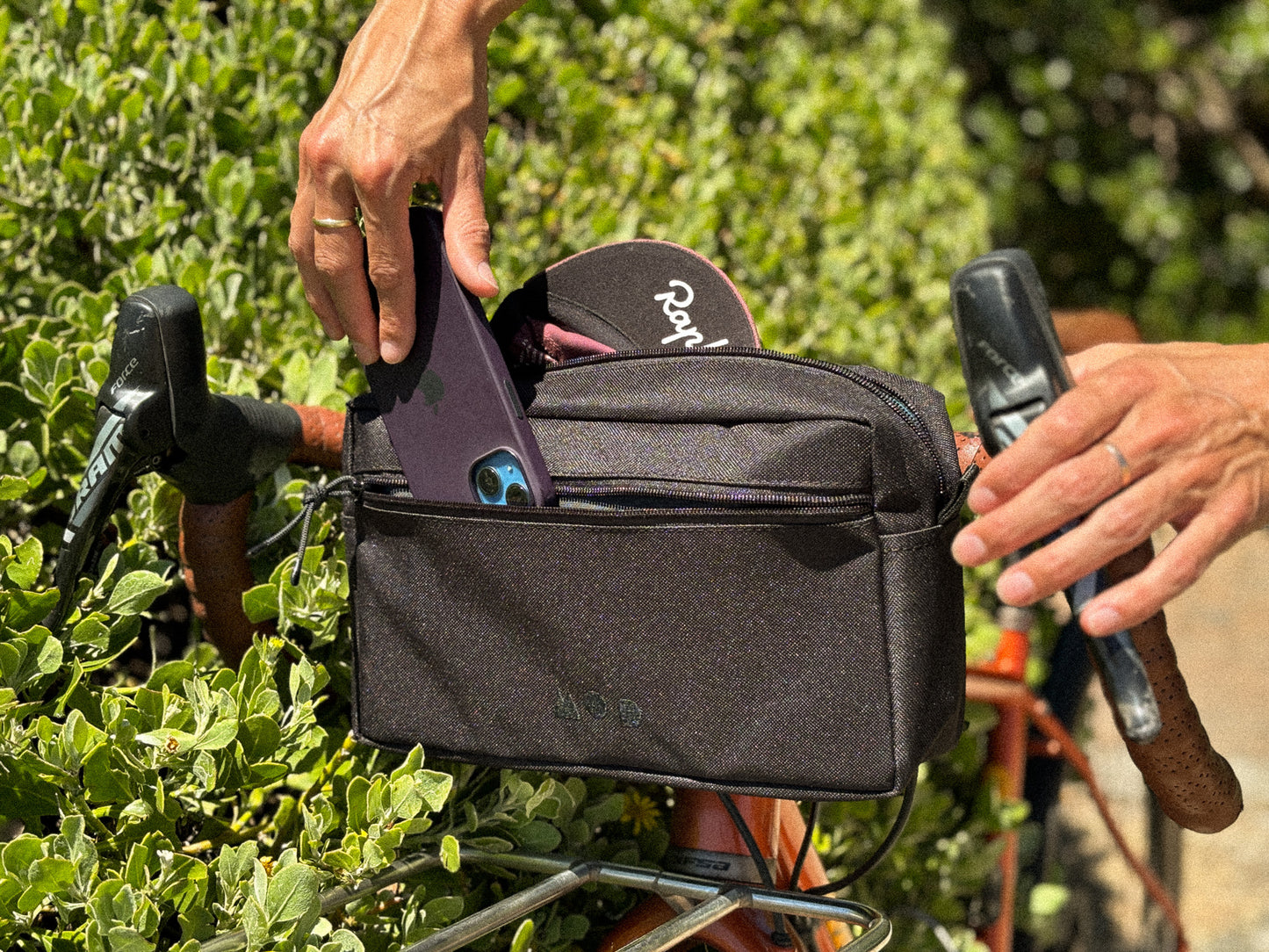 Anywhere Pouch in Black mounted onto bicycle handlebars