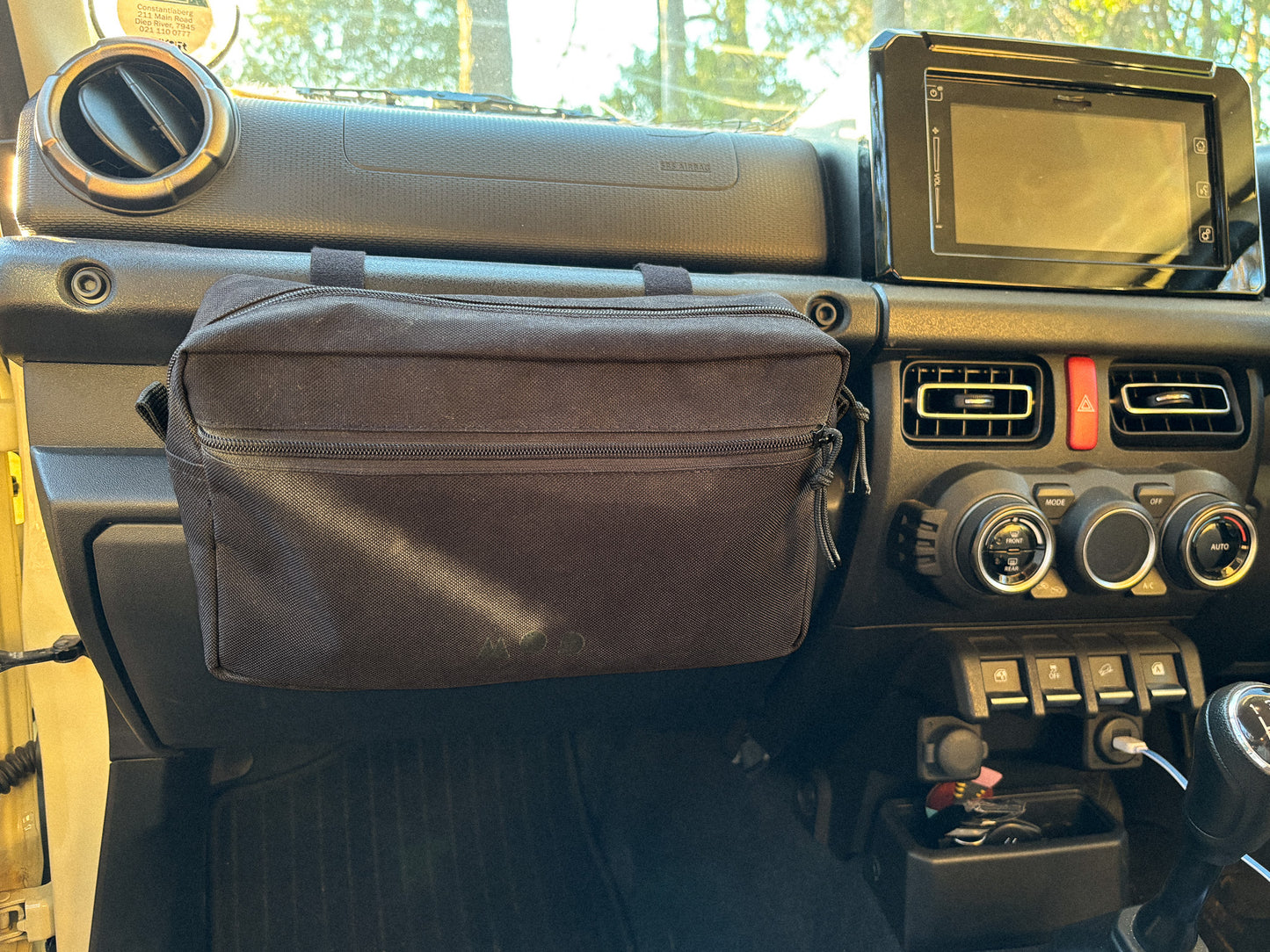 Anywhere Pouch in Black, zipped closed, mounted on a Jimny 4 grab handle