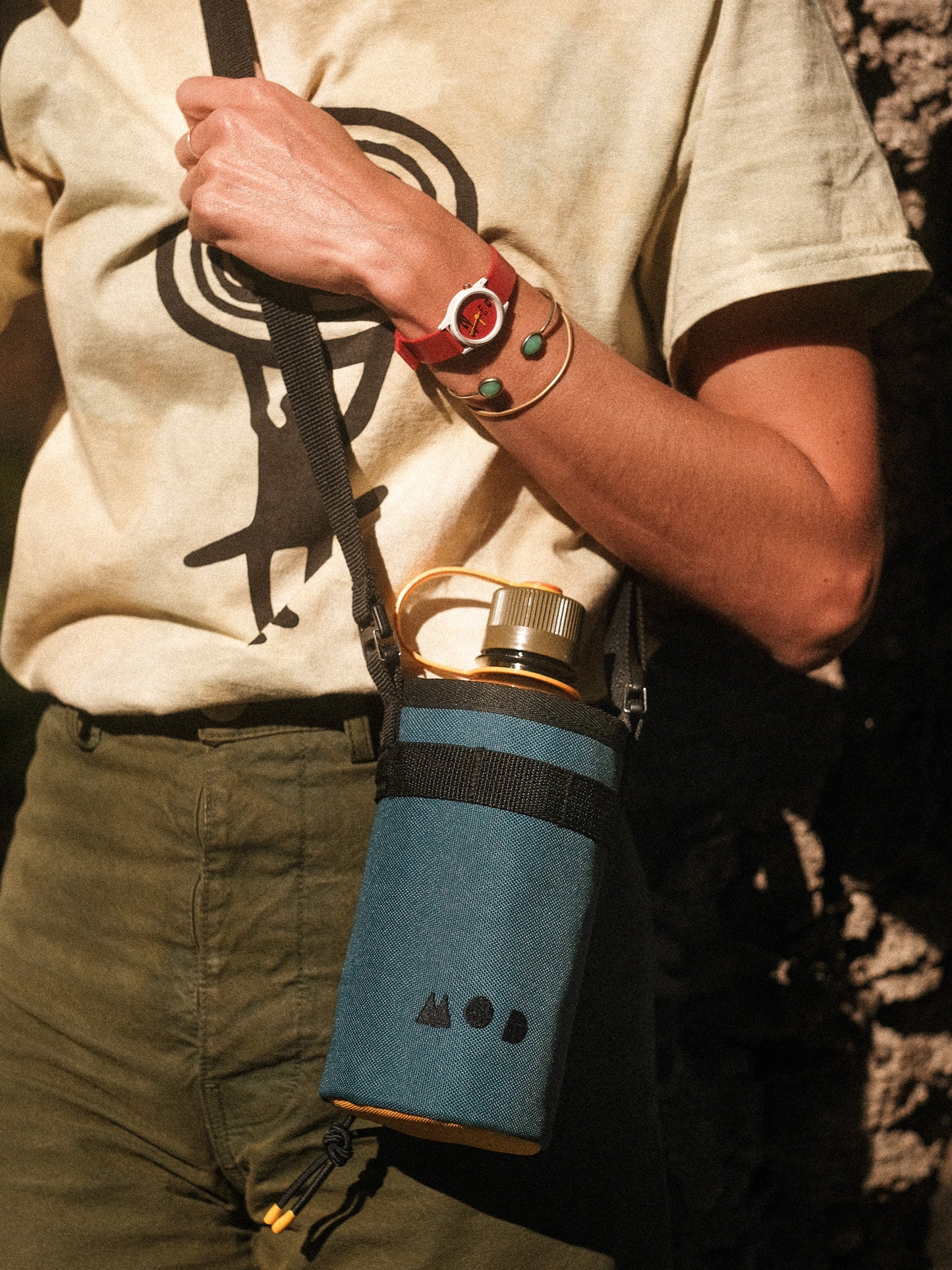 Bottle pouch slung across a body, hiking