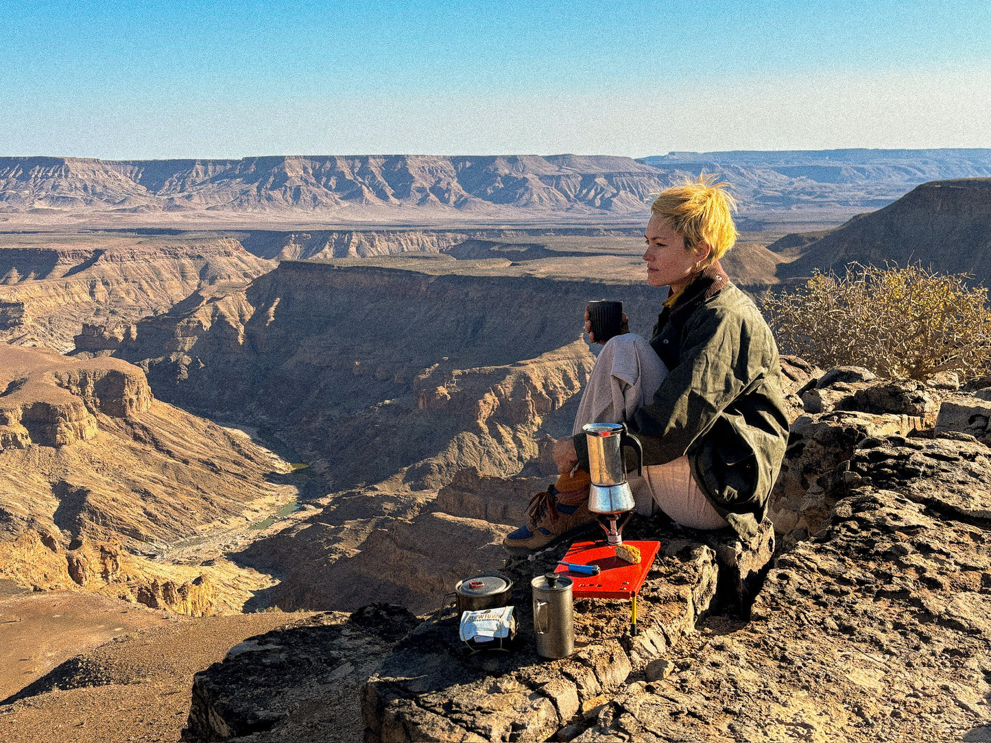 Camp Stove Table with a coffee set up and woman sitting looking at the view