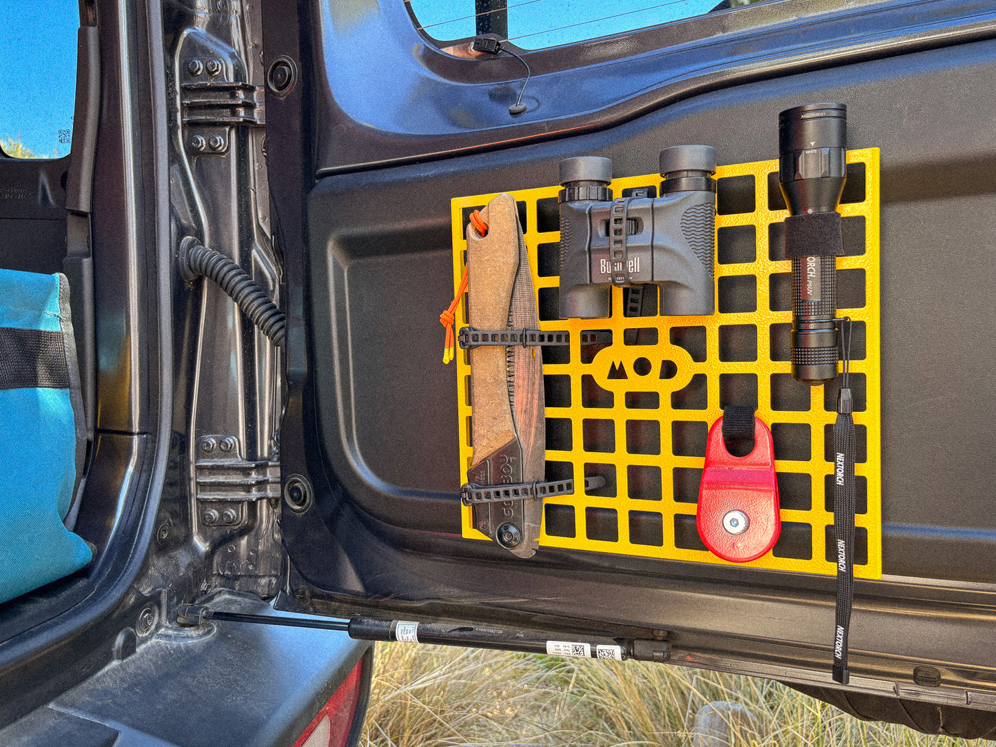 MOD Molly Molle panel installed in Jimny 4 in yellow showing binoculars, torch, saw mounted on molle panel