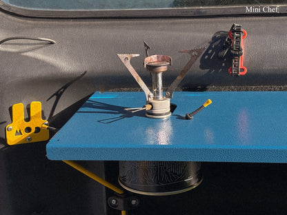 A small portable camping stove sits mounted on a blue rear door table for Jimny. Mini Chef Table for Suzuki Jimny
